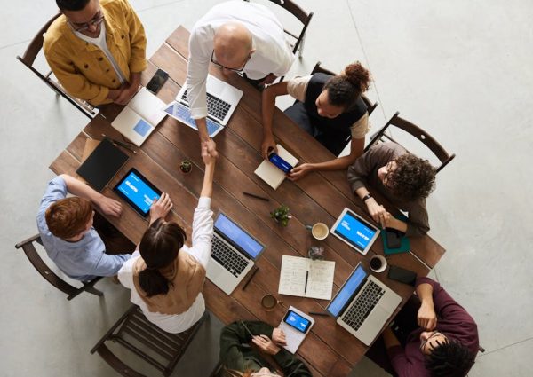 pexels-photo-3183197-3183197 Top view of a diverse team collaborating in an office setting with laptops and tablets, promoting cooperation.